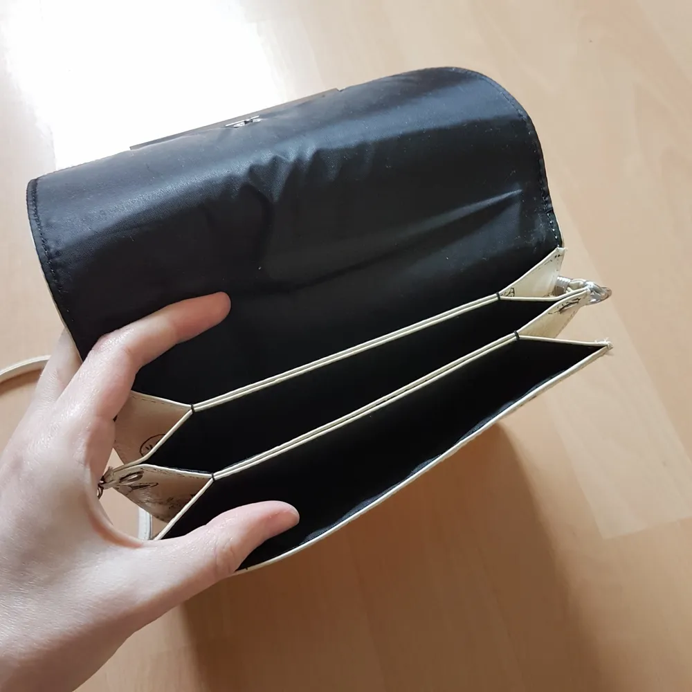 Jättesöt axelbandsväska i en off-white läderimitation, med katter på. Är inte helt säker på vart den är ifrån, men troligtvis Monki. Den är ca 17x19 cm, och har 3 fack.. Asusteet.