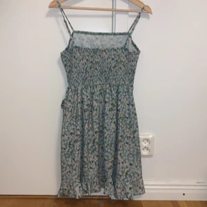 Grön omlottklänning med blommor - Söt omlottklänning med små vita och gula blommor. Väldigt bra skick! 