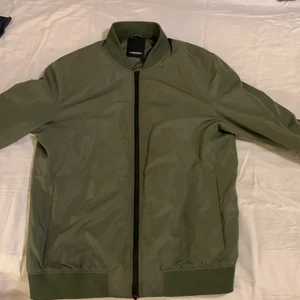 J.Lindeberg Jacka - En grön J.Lindeberg jacka som är i ett nytt skick. Har använt den drygt 10 gnr. Super skön att ha till sena kvällar och bra jacka till vår och höst.