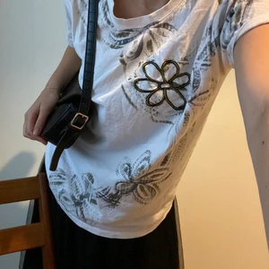 Fin tee med blomdetalj  - Köpte second hand, anonymt märke och skönt material. Känns lite 2005, snygg och unik att stylea med jeans och kjolar! storlek M och sitter såhär på mig ⬆️💕