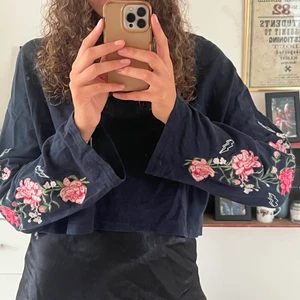 Croppad mörkblå tjocktröja - Mörkblå tjocktröja i kortare modell med broderade blommor på ärmarna 🌸 strl medium!