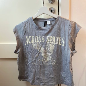 H&M croppad t-shirt (NY) - Helt oanvänd croppad t-shirt med motiv. Skrynklig då den legat i garderoben. I gott skick utan slitage. 