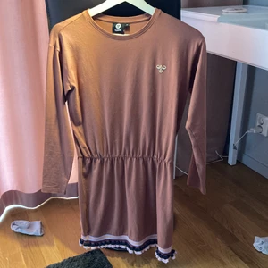 Skön kläning - Klänningen är i färgen korall och har en fin volang kant längst ned på på klänningen. Jag älskar denna klänning men är för liten, använd fåtal gånger. Köparen står för frakten!