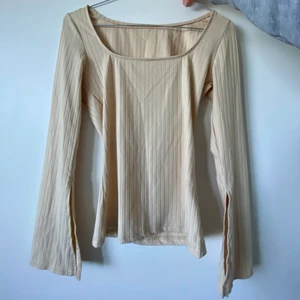 Beige långärmad med volang-arm  - Väldigt snygg tight beige volang-ärmad och urringar tröja i stretchigt material och ribbat mönster ish.
