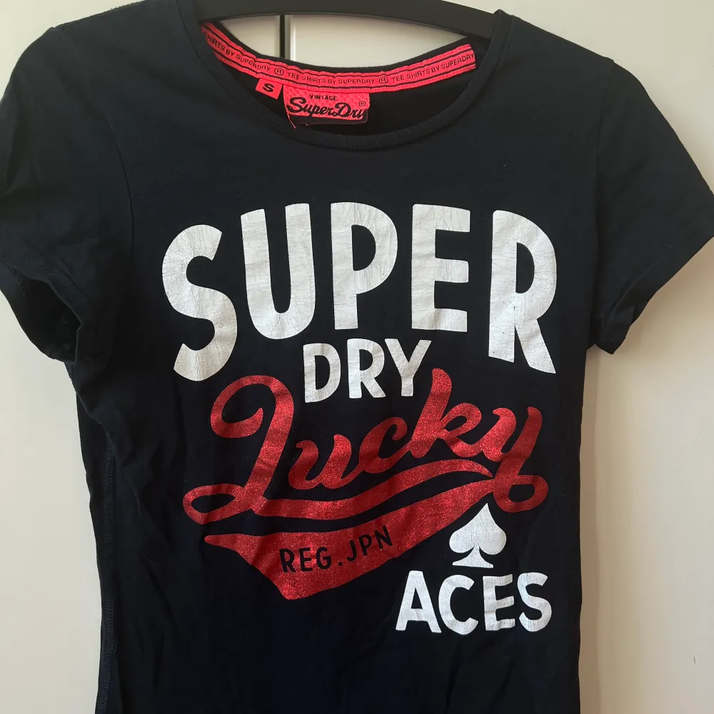 Denna snygga superdry T-shirt säljs nu för att den tyvärr inte längre kommer till användning. Den är svart med vit text. Samt att den röda texten är i glitter. Skriv för mer bilder 😊. T-shirts.