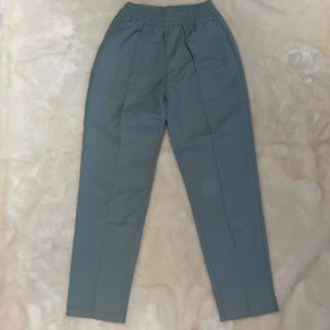 Kostymbyxor  - Extremt sköna kostymbyxor i grönt med resår i midjan! Sitter väldigt fint på kroppen! Använda 1 gång