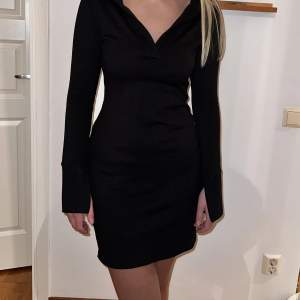 En svart långärmad klänning i lite stickat material med en urringning med ”krage” från Gina Tricot, långa ärmar med slits 