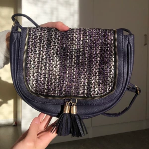 Lila axelväska  - Söt lila/svart axelremsväska i nyskick! Bandet är justerbart. Har en liten ficka på insidan. Frakt tillkommer. Skriv vid frågor 💜