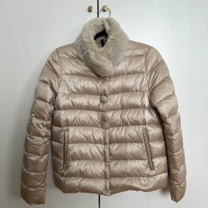 Moncler dunjacka  - Dunjacka från Moncler i storlek 1, passar en XS-M beroende på hur man vill att den ska sitta. Jättefint skick, har ett litet skrapmärke fram, knappt synligt. Champagne/creme färg med matchande päls i kragen. Stängs med tryckknappar och 2 sidfickor. 