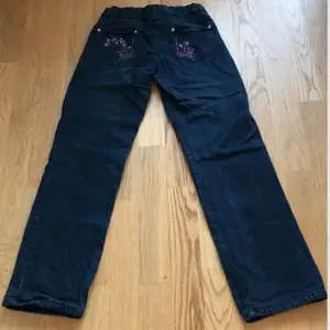 Midjemått: 66 cm Innerbenslängd: 72 cm Mörkblåa lågmidjade jeans med brodering på fickorna. Fint skick utan skador. Kan självklart skicka fler bilder om det behövs.