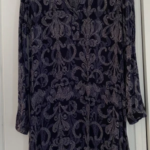 Tunika stl 40 - Tunika i fint skick i stl 40 säljes. Svart i grunden med mönster i lila och beige. 