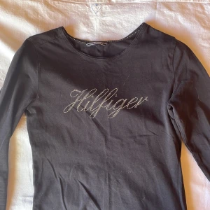 tommy hilfiger långärmad rhinestone tröja - Säljer då den inte används💕 så skönt material! den har tre igensydda hål nere i högra hörnet(se tredje bilden)💕 så fin med ”rhinestonesen”!