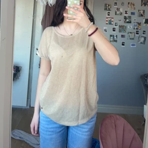 Beige glittrig T-shirt  - Glittrig ganska genomskinlig T-shirt i guld ifrån MOS MOSH. Det är storlek S men jag har S o den sitter oversized. Ordinarie pris :400kr      Nypris: 150kr