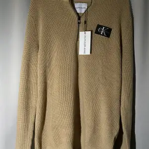 Calvin Klein beige stickad zip up tröja. Bra skick då den inte har används men behöver att stryka. Köpt från kids brand store i strl 170/m. 