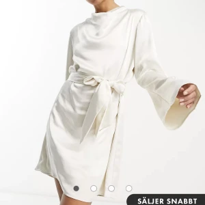 Ostronfärgad miniklänning satin - Pretty lavish  - Klänningen är oanvänd och ny, köptes från ASOS. Passar även bra på en som är runt 168 cm. Bandet vid midjan går att knyta om 🥰