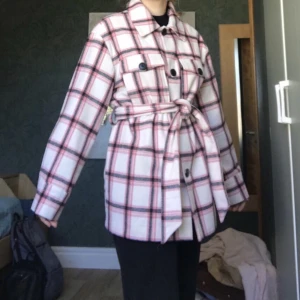 Vårjacka - Superfin rosa-rutig kappa, perfekt för våren. Storlek 36 men den är i oversize-modell så den passar nog 38/M också. Säljer för den kommer sällan till användning.