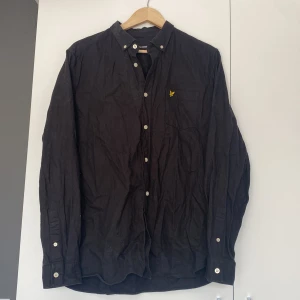 HERR Lyle & Scott skjorta  - Lyle & Scott skjorta. Svart med vita knappar och gult märke. Nypris 599kr. Fint skick men behöver strykas!