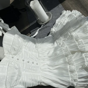 Studentklänning!!🤍⚡️ - Säljer denna magiska (!!) student klänning i storlek 34. Helt oanvänd, köptes då jag skulle byta till den på kvällen men gick aldrig ut:(  otroliga detaljer som volanger ned till med vackra sidenband vid axlarna man knyta själva😍. Lappen är kvar frakt: 62