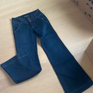Stretchiga low rise jeans i mörkt denim tyg, supersnygga fickor baktill och glitter detaljer i midjan