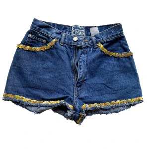 Jenasshorts från Jordache - Säljer dessa coola vintage shorts från Jordache i storlek 7 ( typ 32/34 ), köpta på beyond retro. Knappt använda. Paljetterna sitter lite löst men går både att lätt laga eller sprätta bort. För mer frågor om mått, frakt m.m. är det bara att höra av dig!❣️