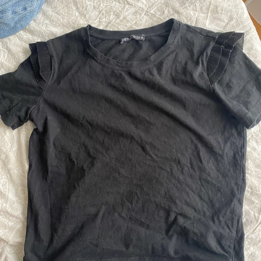 Svart superfin t-shirt från zara med volanger på ärmarna. Den har tyvärr blivit lite för liten för mig så kommer inte till användning. Passar till mycket och kan kläs upp och ner. Skriv för fler bilder.. T-shirts.