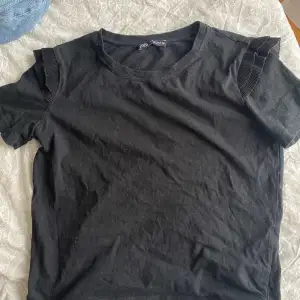 Svart superfin t-shirt från zara med volanger på ärmarna. Den har tyvärr blivit lite för liten för mig så kommer inte till användning. Passar till mycket och kan kläs upp och ner. Skriv för fler bilder.