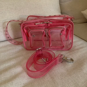 Nuuno väska  - Rosa/transparant väska från Nuuno. Använd endast ett fåtal gånger. Har några små defekter på framsidan men det syns inte så fort man lägger något i väskan! 