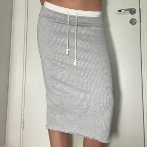 Grå kjol - Grå långkjol med vita detaljer och dragsko/dragsnöre!