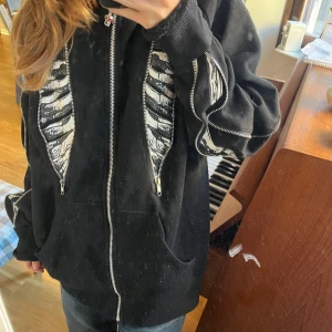 Skeletthoodie - En skitcool skeletthodie med fina detaljer. Köpt på Stockholms stadsmission, men i bra i skick. Står att det är storlek M men passar helt klart L