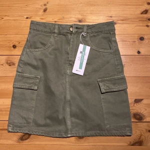 Gröna cargo-liknande Gina tricot jeanskjol - Grön cargo-liknande Gina tricot jeanskjol. Storlek 34. Prislapp kvar så aldrig använd förut, originalpris 300