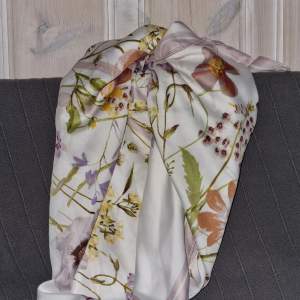 En len vit scarf med blommönster, söt att ha runt halsen eller på huvudet.