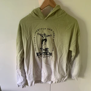 Grön, vit hoodie  - Jätte fin hoodie. Säljer på grund av för liten storlek. Den e grön och vit och det står The Elites på den.