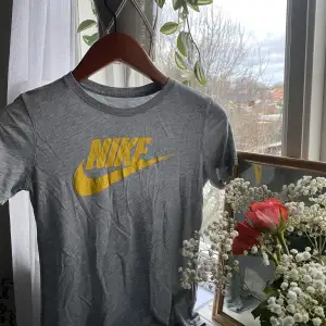 - Grå Nike-tshirt med gult tryck  - Tidigare köpt på Plick  - Åtsittande passform  - OK skick: Slitage på trycket men inget som syns markant vid användning
