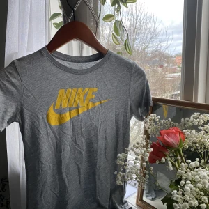 Fitted Niketröja - - Grå Nike-tshirt med gult tryck  - Tidigare köpt på Plick  - Åtsittande passform  - OK skick: Slitage på trycket men inget som syns markant vid användning