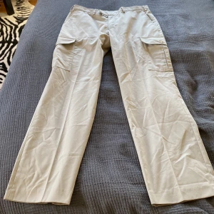 Cargo byxor  - Jättesnygga Cargo pants i ljusgrå färg med bruna detaljer, märket är Rappson. Väldigt fint skick och knappast använda! 