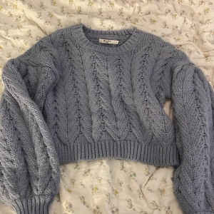 Kabelstickad ljusblå NA-KD tjocktröja - Storlek M. Croppad längd i magen. Breda/puffiga armar