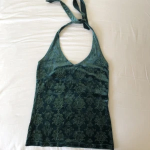Grön sammet halternecktop strl 36/38 - Stretchigt sammetstyg med glitterprägling i indisk paisly mönster. I gott skick, från Lindex i storlek 36/38. Köparen står för frakt men dm:a gärna vid frågor eller funderingar.