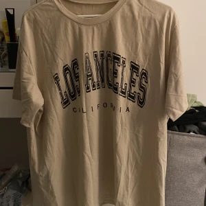 Beige tshirt  - Beige tshirt med ett svart tryck på. Trycket ska se ”slitet” ut och är inget jag gjort själv. Helt oanvänd i strl L. Mjuk o fin. 40kr+frakt 