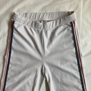 Nike byxor - Vita Nike yoga pants. Snygga genomgående ränder i blått och rött längst sidorna. Något genomskinliga men med rätt trosor under funkar de bra. Strechiga och sköna så funkar både på någon som är S eller M. 