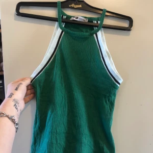 Mörk grönt linne - Mörk grön linne med svart och vita ränder på. Det ska vara ett Mag linne men funkar självklart som vanligt linne också men då för något kortare personer. Det är storlek xxs på men funkar perfekt som xs. 