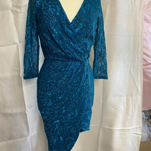 Party klänning  - Denna fina sexiga klänningen passar till tjejen som vågar, den är i spets och draperad i midjanoch har en hög slits. Klänningen är ny och oanvänd i stl 36. Skickas spårbar med postnord.