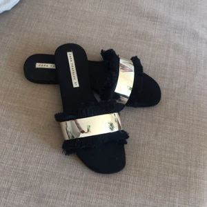 Sandaler/ Slippers - Sandaler/ slippers från zara i strl 37. Är svarta med guld detalj och svarta fransar! Använda så har några repor på insidan, syns inte när man har på sig skorna. Säljs för 40kr 