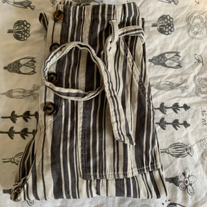 Paper-bag byxa - H&M storlek 36 - Välanvända Offwhite/grå paper-bag byxa i storlek 36. Köpta på H&M för ett antal år sedan. Säljes pga att de blivit för korta för mig. Två större framfickor - inga bakfickor knytband och igensydda knappar i jylfen (se bild 3)