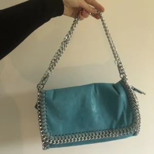 Blå Skimriga väska - Blå Skimriga Stella McCartney liknande väska! Köpt secondhand och medelstor:) går att ha på flera sätt som ni ser på bilderna, möts i Uppsala eller så står köpare för frakt:)