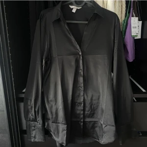 Svart satinskjorta - Från H&M i storlek S, sitter superfint på mig som är xs/s och kan kläs upp o ned🫶🏼 satinliknande material. ANVÄND KÖP NU FÖR GRATIS FRAKT TILL O MED 18 APRIL