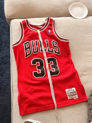 Chicago Bulls tröja #33 Pippen - Säljer ett rött Chicago Bulls basketlinne från Mitchell & Ness Hardwood Classics med nummer 33 och Pippen på bröstet. Linnet har svarta och vita detaljer, NBA-logga och är tillverkat i meshmaterial som andas. Perfekt för basket eller streetwear. SAMLAROBJEKT!!!!! Går för 200$ och uppåt på eBay. Slå till. 