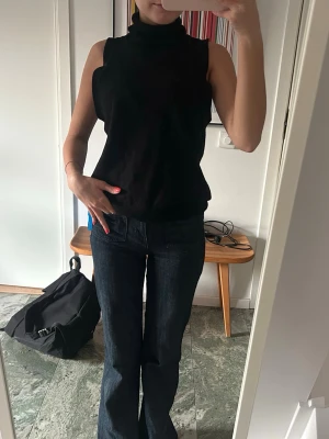 Svart ärmlös polotopp - Snygg svart ärmlös topp i kashmir blend med polokrage. Stor i armöppningen. 