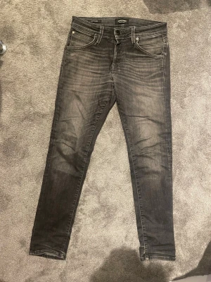 Svart fadade jackjones slimjeans - Säljer ett par svartfadade jackjones jeans i passform slim. De är använda men i gott skick då det enda som fixats är ett litet hål i grenen som ej märks. Strl 28:30