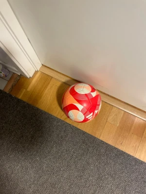 Röd och vit fotboll - Säljer en snygg fotboll i rött och vitt med grafiskt mönster. Perfekt för spontanfotboll med kompisarna eller träning. Tillverkad i slitstarkt syntetmaterial och har klassisk rund form.