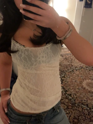 Vit spetslinnetopp med blommönster - Säljer en söt vit linnetopp med blommig spets och tunna axelband. Toppen är figurnära och har ett transparent utseende som ger en trendig vibe. Perfekt att styla med jeans eller kjol för en cool look. Priset står inte i sten så tveka inte på att skicka ett prisförslag❤️